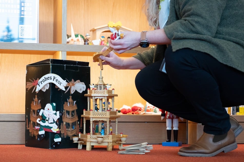 Eine Frau setzt in der Zentralbibliothek Dresden vor einem Regal eine Weihnachtspyramide zusammen.