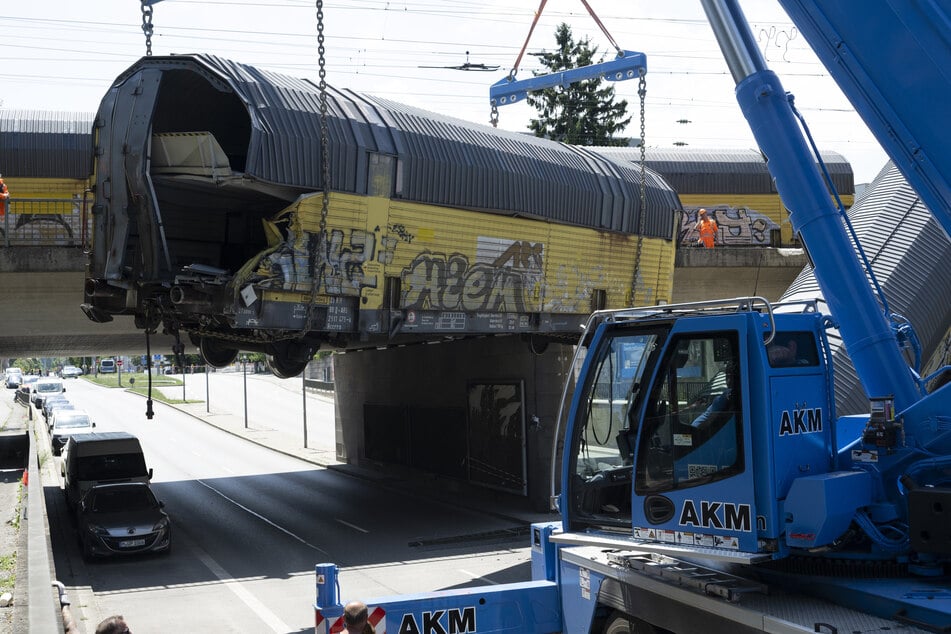 Einer der Waggons wird mit einem Schwerlastkran auf die Straße gehievt.