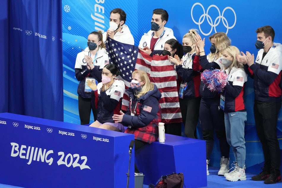 Team USA members react during the women's single free skating portion of the figure skating mixed team final during the Beijing 2022 Olympic Winter Games.