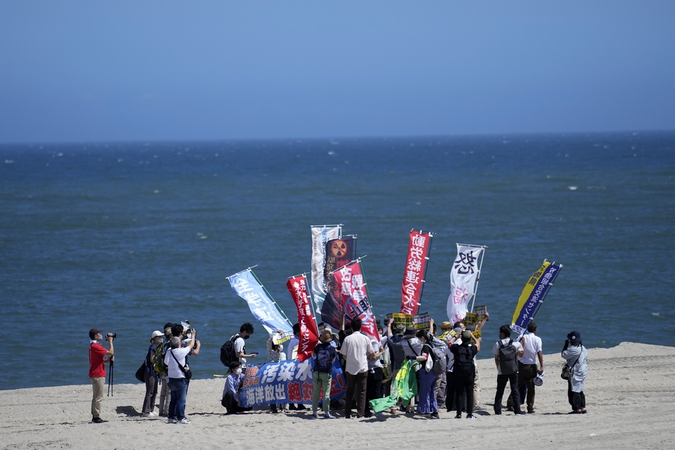 Menschen protestieren an einem Strand in Richtung des Kernkraftwerks Fukushima.