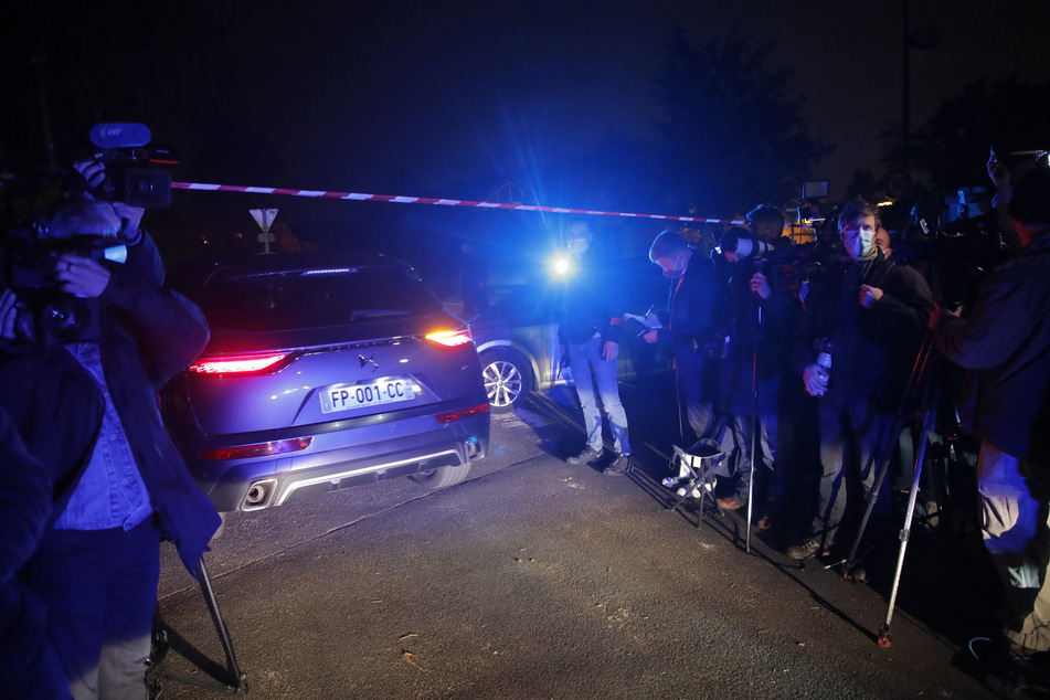 Ein Polizeiauto fährt vorbei an Journalisten am Tatort nach der brutalen Messerattacke.