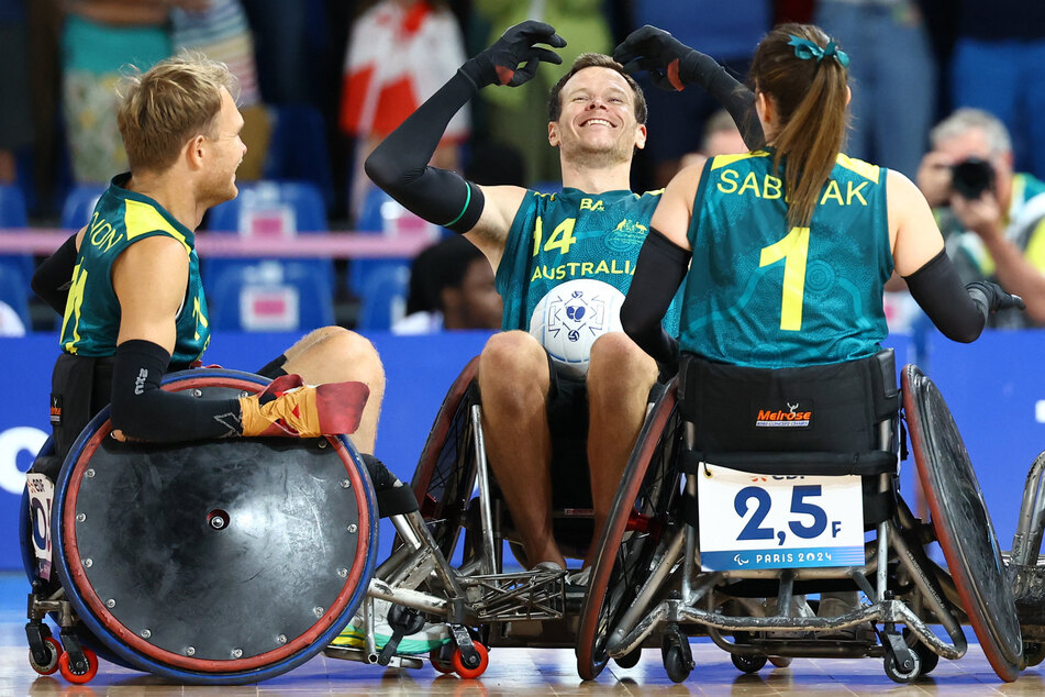 Andrew Edmondson, Beau Vernon, and Ella Sabljak of Australia celebrate winning the bronze medal in wheelchair rugby at the Paris Paralympics.