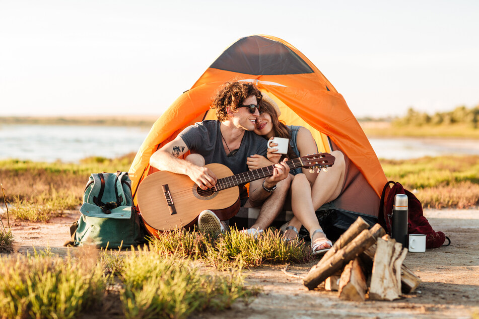 Dieses Paar hat einsam am See sein Zelt aufgeschlagen und will ein Lagerfeuer entzünden. Romantisch. In Deutschland gibt es kein einheitliches Recht zum Wildcampen. Tendenziell ist es aber eher verboten. Also lieber einen Zeltplatz aufsuchen.