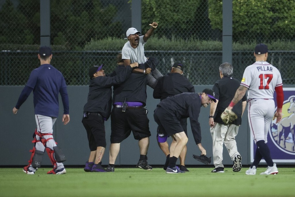 A fan yells to Ronald Acuña Jr. of the Atlanta Braves after running onto the field and being apprehended by security during the game against the Colorado Rockies at Coors Field on August 28, 2023.