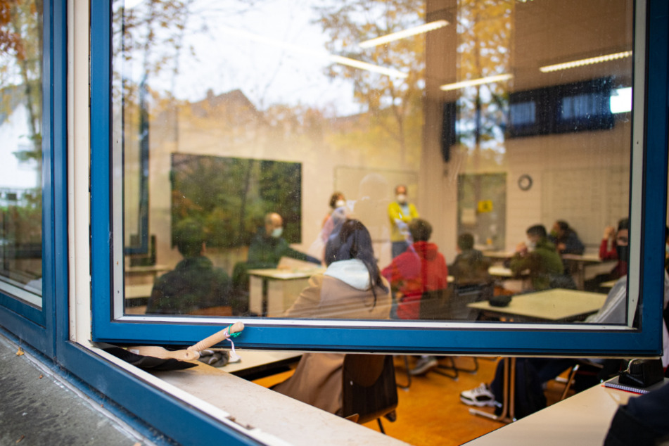 Blick durch das offen stehende Fenster in den Klassenraum einer Schule.
