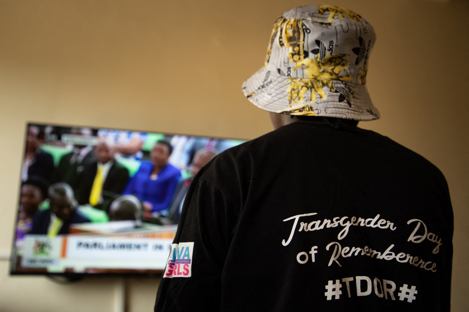 A Ugandan transgender woman – who was recently attacked – watches a TV screen showing the live broadcast of the anti-gay bill's passage.