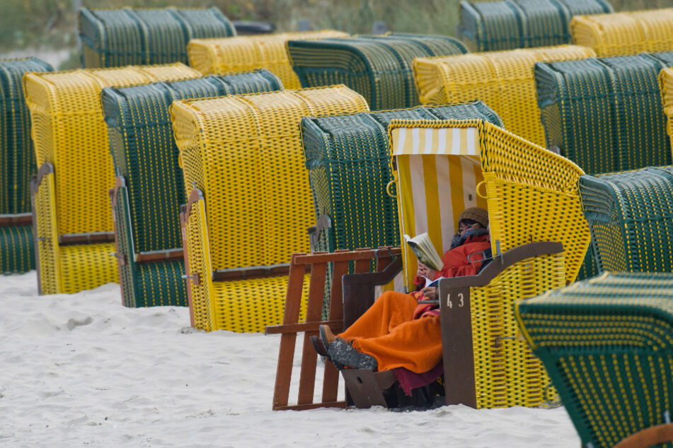 Ein Tourist sitzt dick eingepackt in einem Strandkorb (Archivbild).