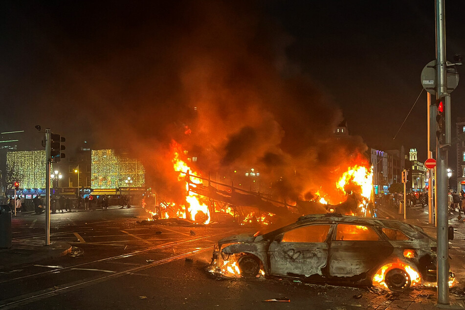 A Dublin roadway burns as flames rise from a car and a bus set alight by rioters on Thursday.