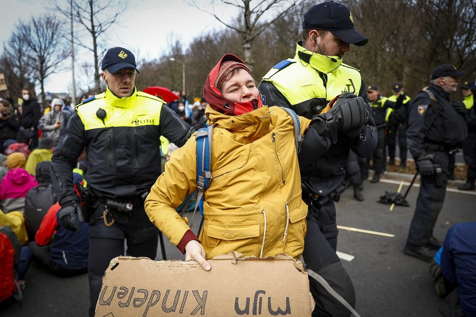 Polizisten tragen eine Aktivistin von der Fahrbahn.