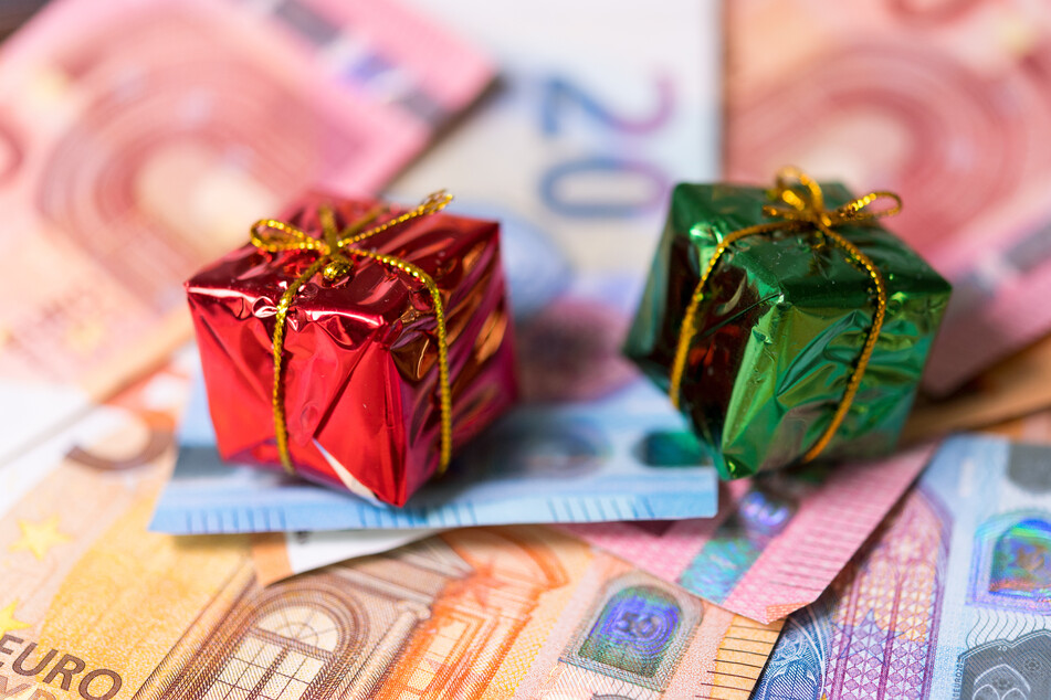 Zwei kleine Geschenke liegen auf zahlreichen Banknoten.