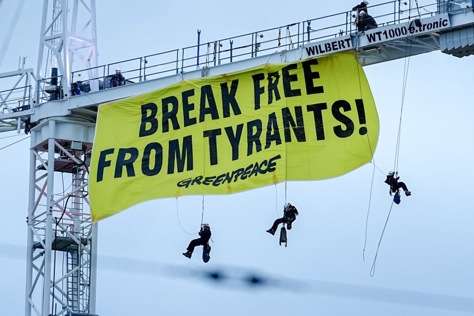 Aktivisten von Greenpeace seilen sich von einem Kran mit einem Banner mit der Aufschrift "Break free from tyrants".