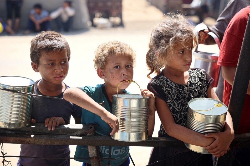 Hungry Palestinian children wait for food being distributed at a camp for internally displaced people in Khan Younis in the southern Gaza Strip.