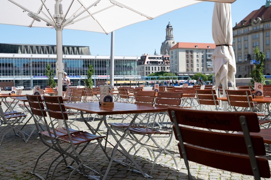 Sachsen, Dresden: Tische und Stühle stehen im Außenbereich eines Restaurants auf dem Altmarkt vor der Frauenkirche.