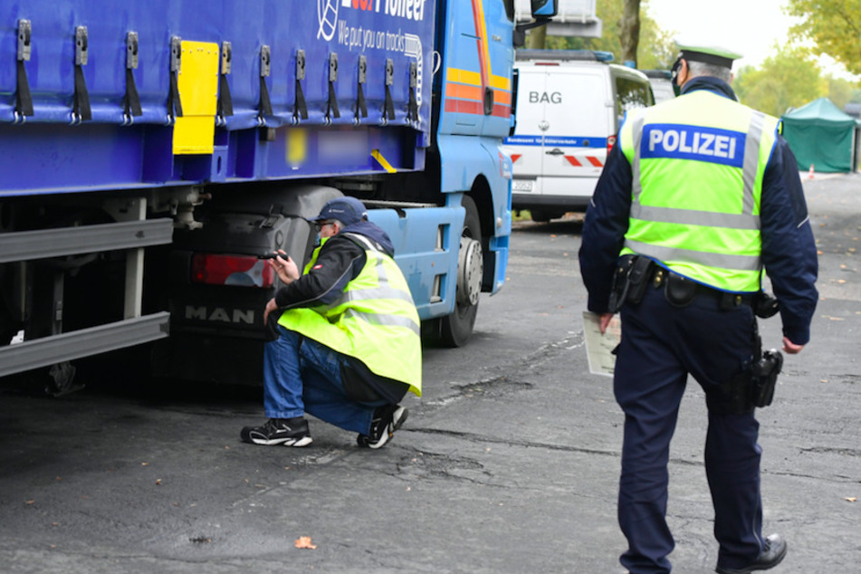 Polizisten kontrollieren bei einem Lkw die Bremsen. (Symbolbild)