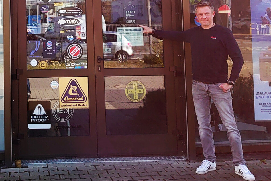 Heiko Geisen deutet auf das "Closed"-Schild an seinem Laden in der Wächtersbacher Straße in Frankfurt