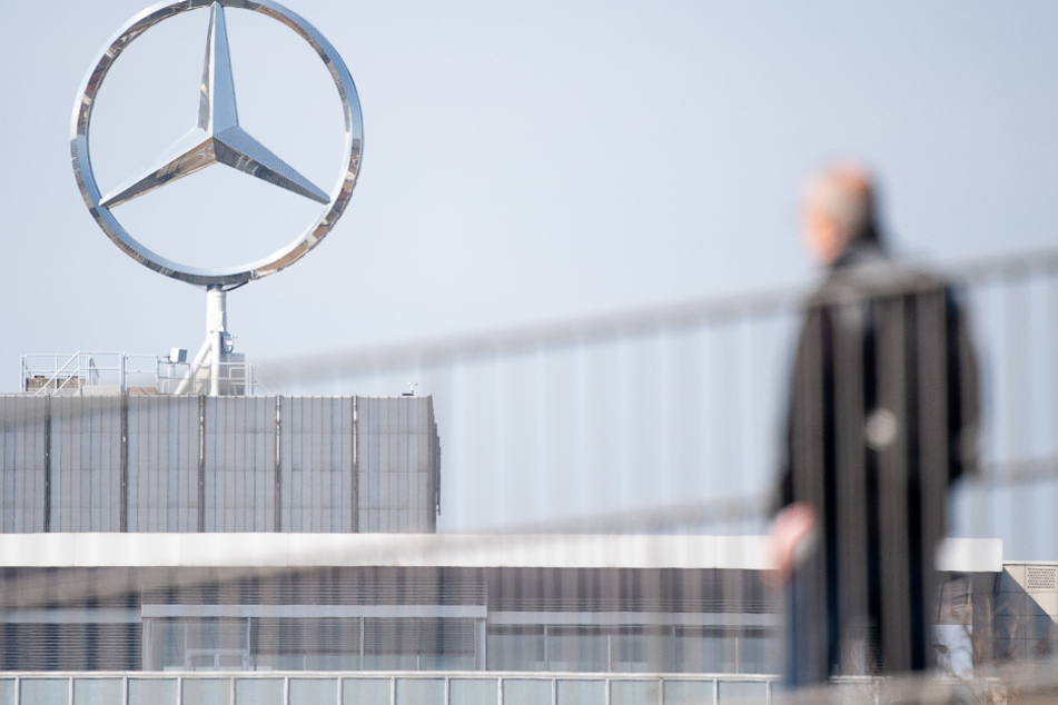 Ein Mitarbeiter von Daimler geht am Mercedes-Benz Werk Untertürkheim zum Schichtwechsel vor einem Mercedes-Stern Richtung Werk.