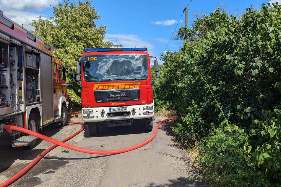 Feuerwehrautos am Weg neben der Wiesenfläche.