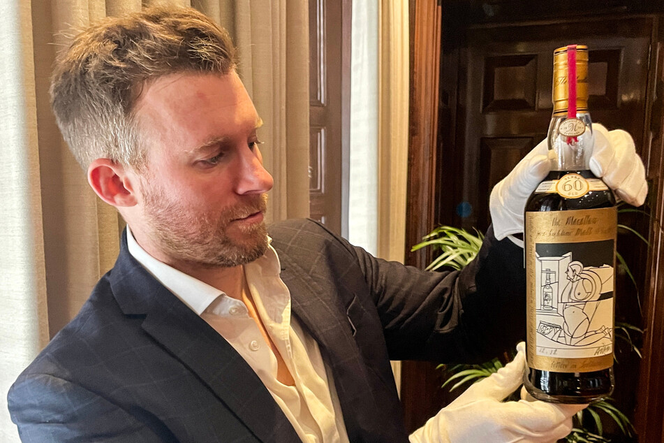 A staff member shows off a bottle of the Macallan Valerio Adami 60 Year Old 42.8 abv 1926, the world's most valuable whisky, which went under the hammer for a record $2.7 million and set a "new record for any bottle of spirit or wine sold at auction."