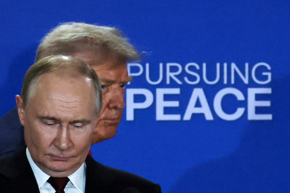 US President Donald Trump (behind) and Russian President Vladimir Putin hold a press conference following their meeting to negotiate an end to the war in Ukraine, at Joint Base Elmendorf-Richardson in Anchorage, Alaska, on August 15, 2025.