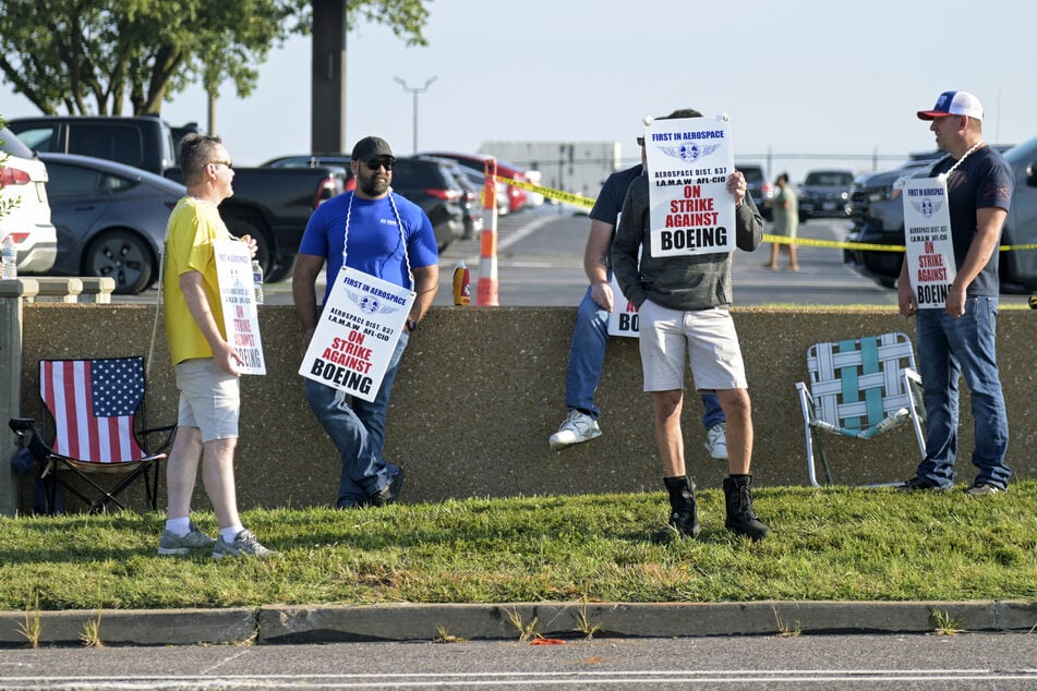 Boeing defense plant workers raise signs as they strike outside of a facility in Berkeley, Missouri.