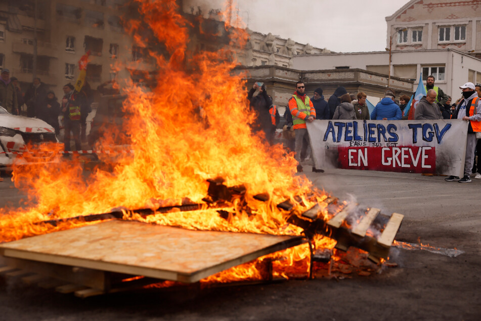 Menschen demonstrieren am Pariser Bahnhof Gare de Lyon in der Nähe von brennenden Paletten.