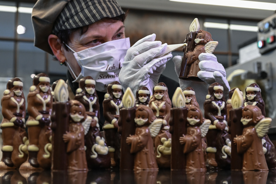 Anne Walter, Chocolatier von der Confiserie Felicitas, dekoriert mit flüssiger weißer Schokolade kleine Weihnachtsfiguren mit einem Mund- Nasenschutz.
