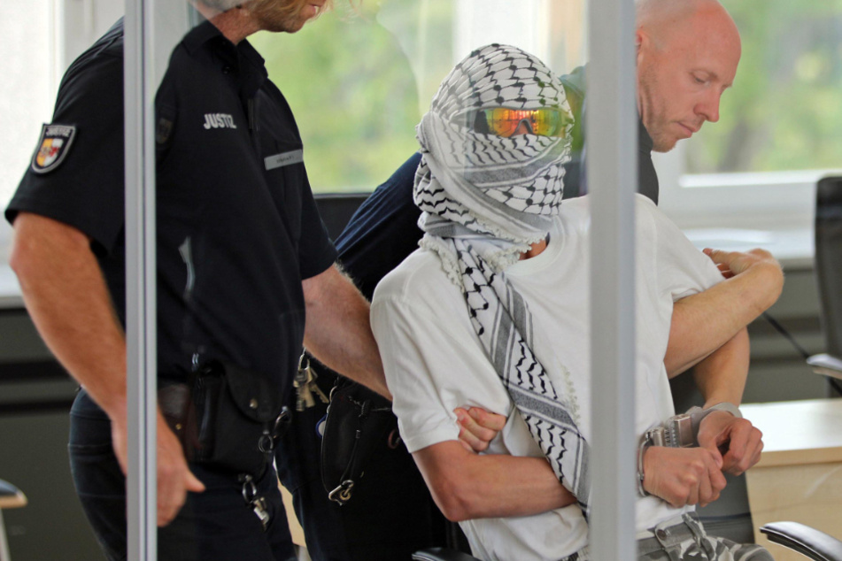 Justizbeamte bringen den Angeklagten in den Gerichtssaal.