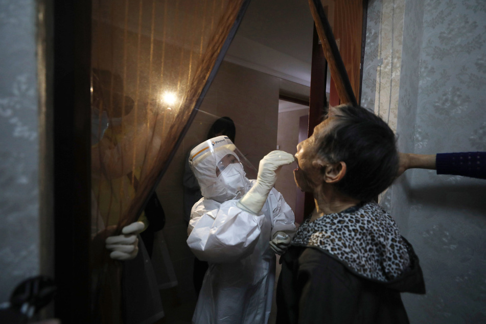 Ein medizinischer Mitarbeiter entnimmt einer Frau bei einem Hausbesuchen in Wuhan (China) einen Abstrich für einen Coronavirus-Test. Wuhan gilt als Epizentrum des Corona-Ausbruchs. Trump wirft der WHO schwere Versäumnisse in der Corona-Krise und China-Hörigkeit vor.