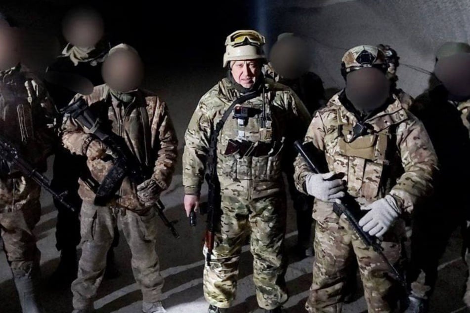 Jewgeni Prigoschin (M.) posiert mit seinen Soldaten in einem dunklen Keller.