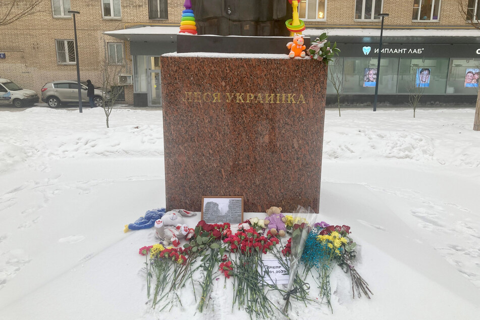 Ein Mahnmal vor dem Denkmal der ukrainischen Dichterin Lessja Ukrajinka in der russischen Hauptstadt Moskau erinnert mit einem Foto und Blumen an das zerstörte Wohnhaus in Dnipro und die bisher 45 Todesopfer.