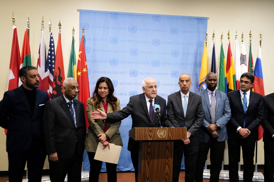 Palestinian Ambassador to the United Nations Riyad Mansour (c.) was joined by representatives of Arab countries after a vote to approve a resolution that "demands" all sides in the Israel-Gaza conflict allow the "safe and unhindered delivery of humanitarian assistance at scale" at the UN in New York on Friday.