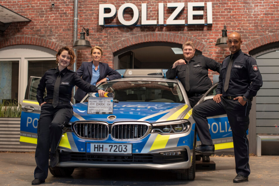 Wanda Perdelwitz (von links nach rechts), Saskia Fischer, Marc Zwinz und Patrick Abozen posieren zum Drehstart der 34. "Großstadtrevier"-Staffel an einem Polizeiauto.