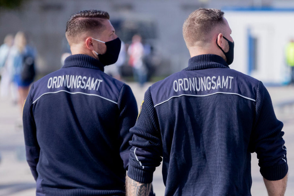 Mitarbeiter des Ordnungsamtes mit Mund-Nasen-Schutz patrouillieren auf dem Stadtplatz Neuer Lustgarten in Potsdam.