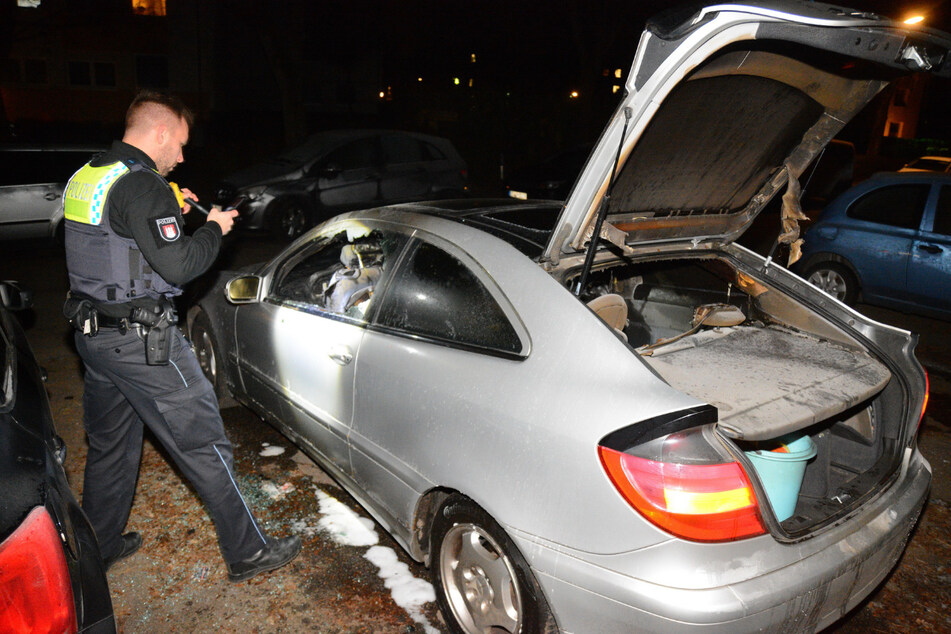 Ein Polizist untersucht den gelöschten Mercedes.