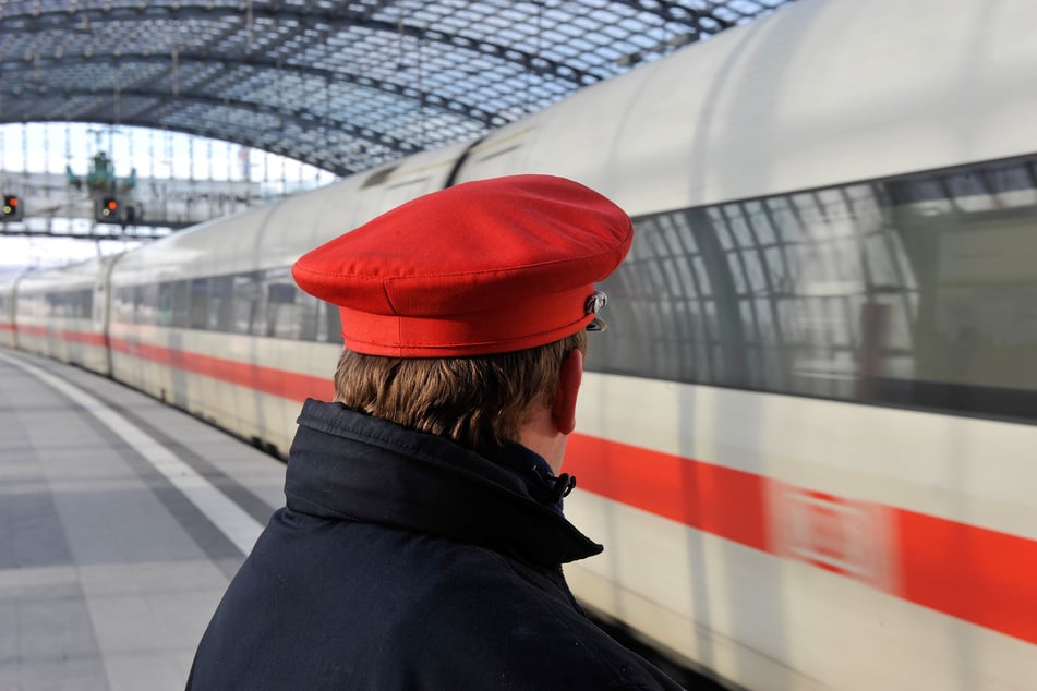 Ein Bahn-Mitarbeiter steht im Berliner Hauptbahnhof am Bahnsteig an einem einfahrenden ICE.