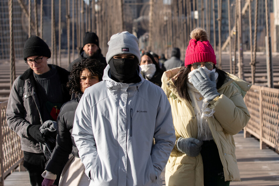 Those braving freezing cold temperatures walked across the Brooklyn Bridge through high winds in New York City on Friday, as deep cold spread across the Northeast.