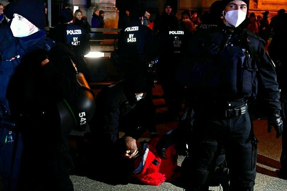 Die Polizei nimmt einen Mann bei der Demo am Mittwochabend in München fest.