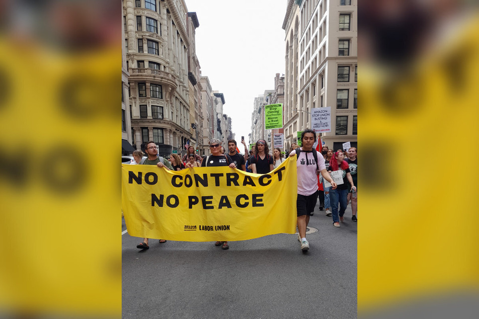 Amazon organizer Heather Goodall (c.) marches through New York City with an Amazon Labor Union banner.