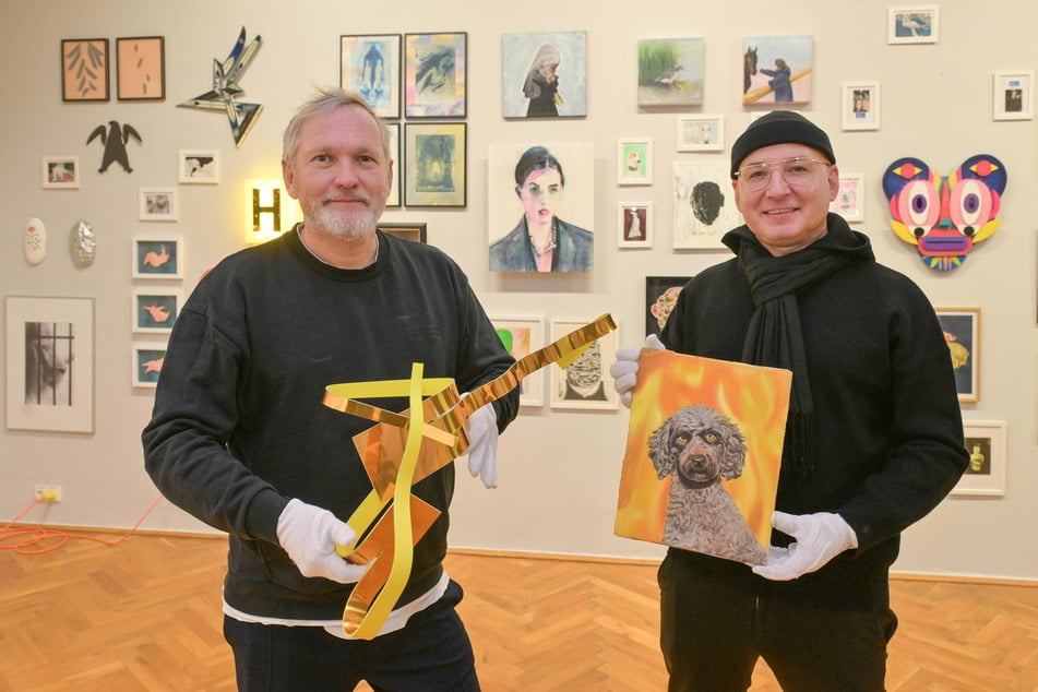 Jens Heinrich Zander (l.) zeigt die Dibond-Arbeit "Cut-G-2" von Jan Großmann, Sören Schürer-Zander hält den "Höllenhund" von Nicolas Dupont.