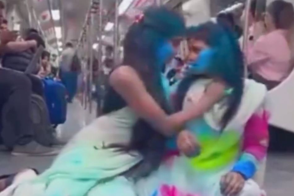 Die beiden jungen Frauen zelebrieren ihren Auftritt in der gut gefüllten U-Bahn.