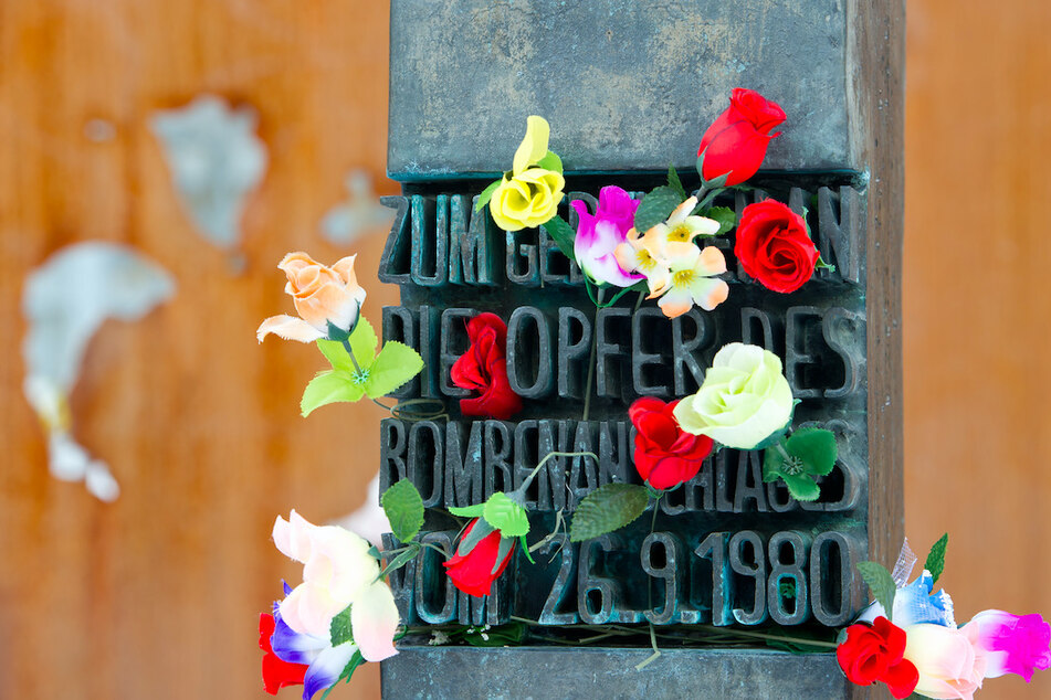 Blumen stecken an einem Denkmal am Haupteingang der Theresienwiese, das an die Opfer des Attentats auf das Oktoberfest erinnert.