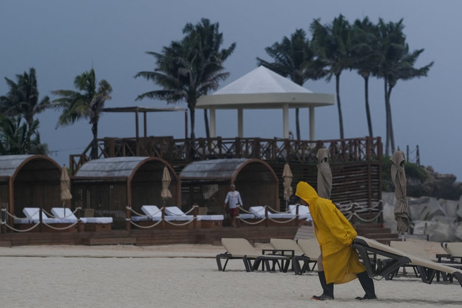 A hotel worker removes a lounge chair as Tropical Storm Helene approaches the Yucatan Peninsula, in Cancun, Mexico, on Tuesday.