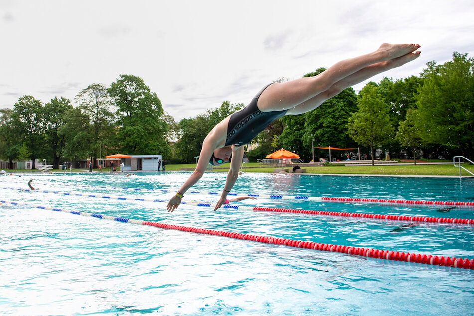 Studentin Corinna springt zum Auftakt der Fraibadsaison im Münchner Schyrenbad vom Startblock in das Schwimmbecken.