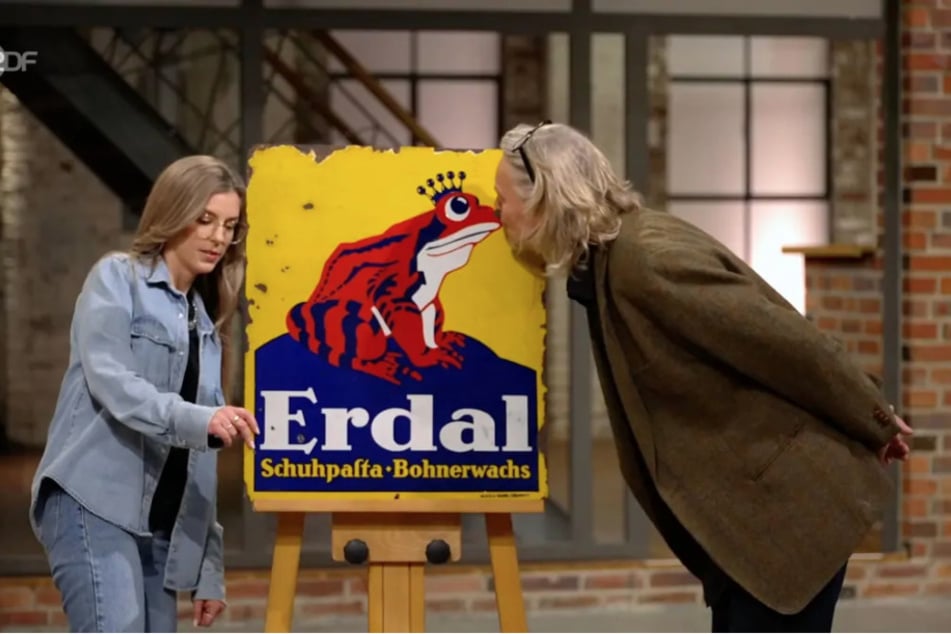Der Kuss bringt ihm zwar keine Prinzessin, aber den Zuschlag: Händler Jos van Katwijk zahlt 550 Euro für die alte Reklametafel.