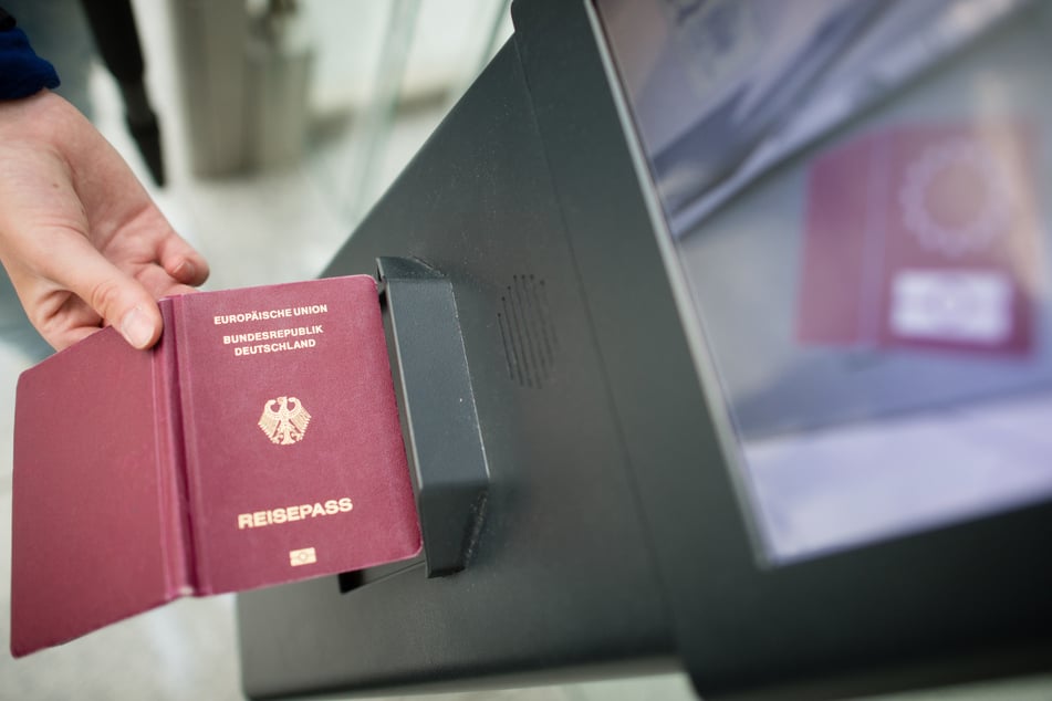 Eine Frau hält einen Reisepass an das Lesegerät eines EasyPass-Systems zur teilautomatisierten Grenzkontrolle am Flughafen in München.