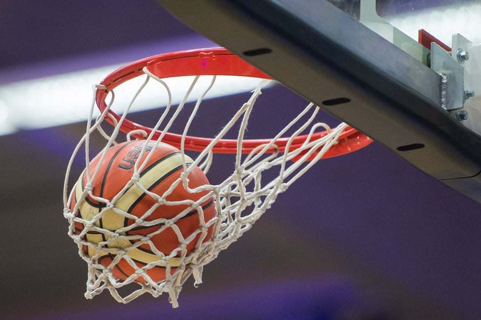 Ein Basketball fliegt in einen Korb.