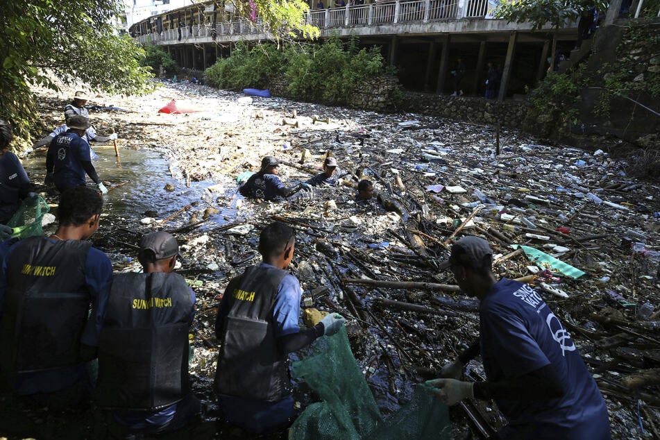 Freiwillige sammeln Müll aus einem Fluss in Pecatu auf.