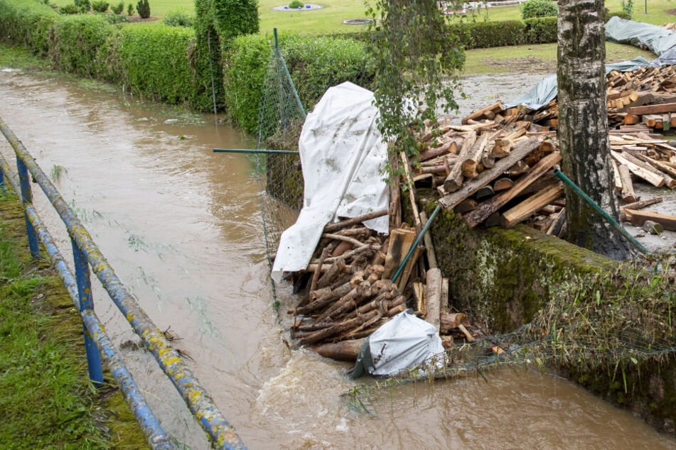 Holz liegt auf einem Haufen neben einem Bach, angespült durch einen Dammbruch.