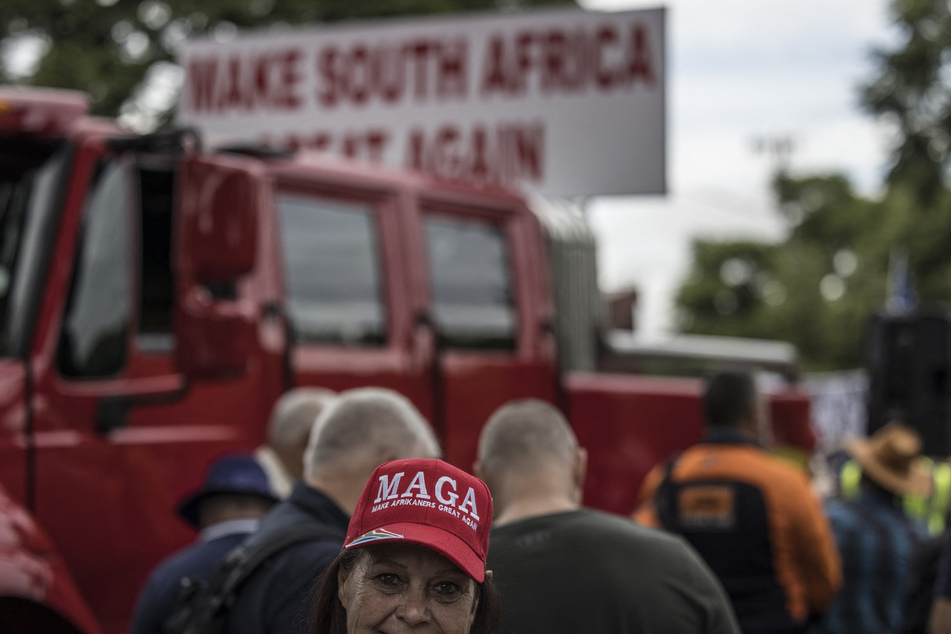 A woman wears a red "Make Afrikaners Great Again" cap as white South Africans supporting Donald Trump and Elon Musk gather in front of the US Embassy in Pretoria.