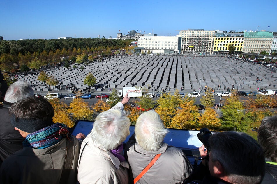 In den Ministergärten in Berlin blicken Besucher auf das Holocaust-Mahnmal.